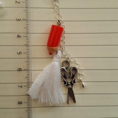 Crayon rouge, pompon blanc en coton et ciseaux argenté. Longueur totale environ 8 cm.