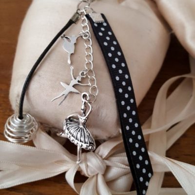 Porte-clefs ou bijoux de sac avec galon gros grain noir à poids blanc , perle en cage de couleur ivoire avec cordon ciré noir et trois breloques danseuses.
Longueur totale environ 12 cm