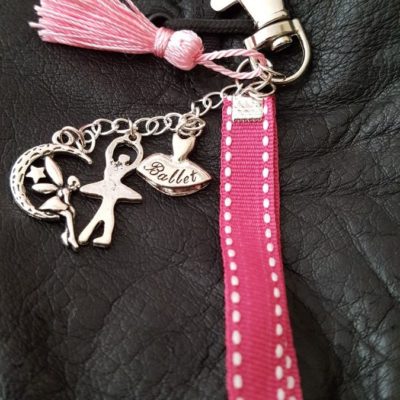 Porte-clefs fermé par un mousqueton . Il se compose d'un pompon rose en soie ,d'un galon gros grain rose fushia ainsi que de trois breloques: un tutu "ballet", une danseuse et d'une fée lune. Longueur totale environ 12 cm