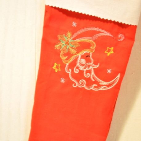 Gros plan. Chaussette de Noël brodée dune lune sur tissu rouge. Création artisanale