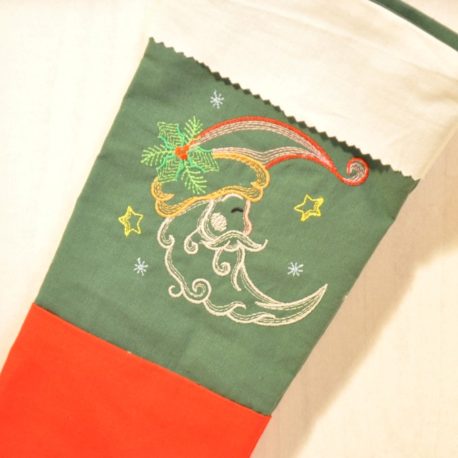 Gros plan. Chaussette de Noël brodée dune lune sur tissu vert. Création artisanale