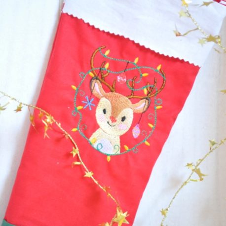 Petit renne de Noël brodée sur du tissu rouge. Gros plan. Création artisanale Bébé Boutchou
