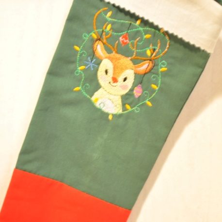 Petit renne de Noël brodée sur du tissu vert. Gros plan. Création artisanale Bébé Boutchou