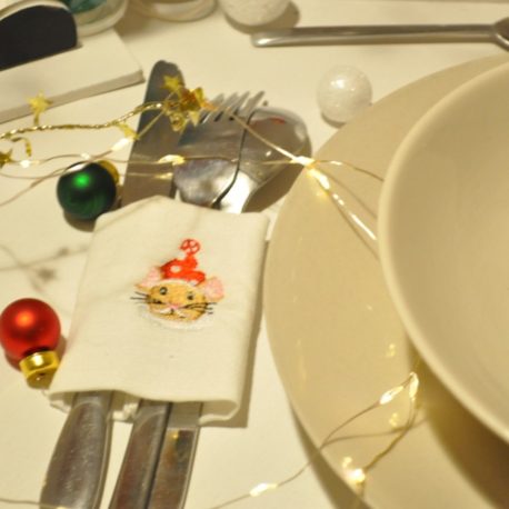 Suggestion en gros plan de présentation. Broderie petite souris de Noël sur rond de serviette en tissu pour couverts. Création artisanale Bébé Boutchou