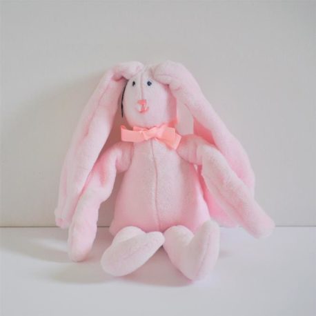 Doudou polaire rose assis contre un mur